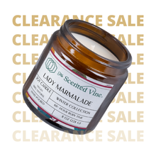 Load image into Gallery viewer, Jar of candle labeled 'Lady Marmalade' from 'The Scented Vine' with a clearance sale text overlay.